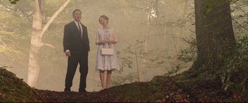 Movie still from “Legend” (2015), directed by Brian Helgeland – A man and a woman standing on a hill in the woods; Wide shot, Low angle