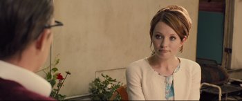 Movie still from “Legend” (2015), directed by Brian Helgeland – A beautiful young woman sitting in front of a plant; Close Up shot, Over the shoulder angle