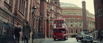 Movie still from “Legend” (2015), directed by Brian Helgeland – A red double decker bus driving down a street; Extreme Wide shot, Low angle