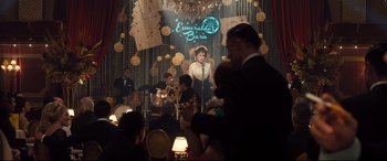 Movie still from “Legend” (2015), directed by Brian Helgeland – A group of people sitting in front of a stage; Wide shot, Over the shoulder angle