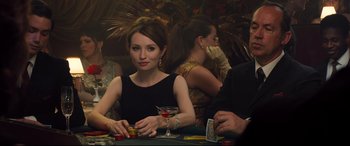 Movie still from “Legend” (2015), directed by Brian Helgeland – A woman sitting at a table with a glass of wine; Medium shot, Over the shoulder angle