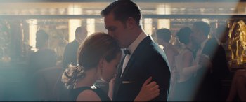 Movie still from “Legend” (2015), directed by Brian Helgeland – A man and a woman kissing in front of a crowd; Medium shot, Low angle
