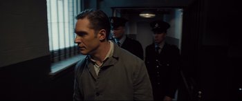 Movie still from “Legend” (2015), directed by Brian Helgeland – A group of men standing next to each other in a room; Medium shot, Over the shoulder angle