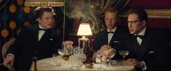 Movie still from “Legend” (2015), directed by Brian Helgeland – A man and a woman sitting at a dinner table; Medium shot, Low angle