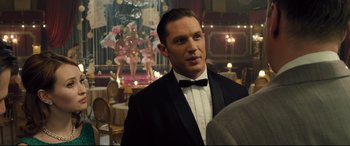 Movie still from “Legend” (2015), directed by Brian Helgeland – A man in a tuxedo standing in a room; Close Up shot, Over the shoulder angle
