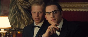Movie still from “Legend” (2015), directed by Brian Helgeland – A couple of men standing next to each other in a room; Close Up shot, Low angle
