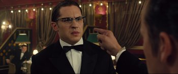 Movie still from “Legend” (2015), directed by Brian Helgeland – A man in a tuxedo pointing at a man in a suit; Close Up shot, Over the shoulder angle