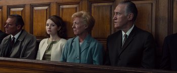 Movie still from “Legend” (2015), directed by Brian Helgeland – Three people sitting in front of a wooden wall; Medium shot, Low angle
