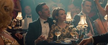 Movie still from “Legend” (2015), directed by Brian Helgeland – A man and a woman sitting next to each other at a table; Medium shot, Over the shoulder angle