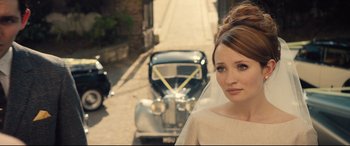 Movie still from “Legend” (2015), directed by Brian Helgeland – A beautiful young woman standing in front of an old car; Close Up shot, Over the shoulder angle