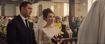 Movie still from “Legend” (2015), directed by Brian Helgeland – A woman in a white dress holding a bouquet of flowers; Close Up shot, Over the shoulder angle