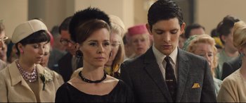 Movie still from “Legend” (2015), directed by Brian Helgeland – A man and a woman standing next to each other in front of a crowd; Close Up shot, Low angle
