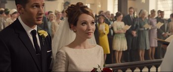 Movie still from “Legend” (2015), directed by Brian Helgeland – A woman in a white dress with a bouquet of roses; Close Up shot, Over the shoulder angle