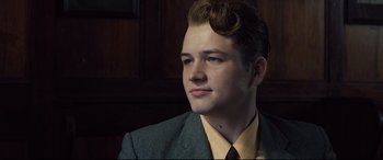 Movie still from “Legend” (2015), directed by Brian Helgeland – A man in a suit and tie looking to his left; Close Up shot, Low angle