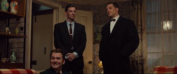 Movie still from “Legend” (2015), directed by Brian Helgeland – A group of men standing next to each other in a room; Medium shot, High angle