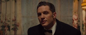 Movie still from “Legend” (2015), directed by Brian Helgeland – A person wearing a suit and bow tie; Close Up shot, Over the shoulder angle