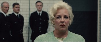 Movie still from “Legend” (2015), directed by Brian Helgeland – An older woman and a young man standing in front of a brick wall; Close Up shot, Low angle