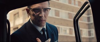 Movie still from “Legend” (2015), directed by Brian Helgeland – A man in a suit and tie holding a ring in his hand; Close Up shot, Over the shoulder angle