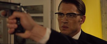 Movie still from “Legend” (2015), directed by Brian Helgeland – A person wearing a suit and glasses; Close Up shot, Over the shoulder angle