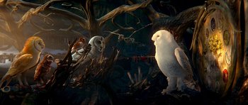 Movie still from “Legend of the Guardians: The Owls of Ga'Hoole” (2010), directed by Zack Snyder – A white owl standing next to a tree with other birds; Wide shot, Low angle