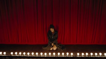 Movie still from “Lemonade” (2016), directed by Mark Romanek – A woman sitting on a stage with candles in front of a curtain; Wide shot, High angle