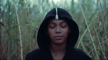 Movie still from “Lemonade” (2016), directed by Mark Romanek – A woman with her eyes closed wearing a black hoodie; Close Up shot, Low angle