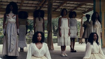 Movie still from “Lemonade” (2016), directed by Mark Romanek – A group of women in white dresses standing under a wooden structure; Wide shot, Over the shoulder angle