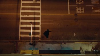 Movie still from “Lemonade” (2016), directed by Mark Romanek – A person riding a skate board on top of a street; Extreme Wide shot, Overhead angle