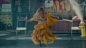 Movie still from “Lemonade” (2016), directed by Mark Romanek – A woman in a yellow dress is dancing in the rain; Wide shot, Low angle