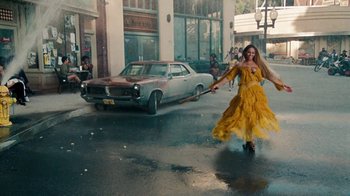 Movie still from “Lemonade” (2016), directed by Mark Romanek – A woman in a long yellow dress holding a broom; Wide shot, High angle