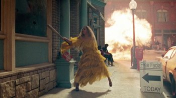 Movie still from “Lemonade” (2016), directed by Mark Romanek – A woman in a yellow dress holding a baseball bat on a street; Wide shot, Over the shoulder angle