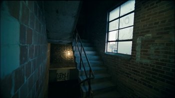 Movie still from “Lemonade” (2016), directed by Mark Romanek – A dark room with stairs leading up to a window; Wide shot, High angle