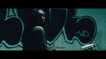 Movie still from “Lemonade” (2016), directed by Mark Romanek – A woman sitting in front of a drum set in front of a wall; Medium shot, Low angle