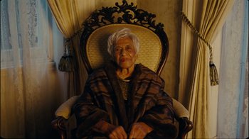 Movie still from “Lemonade” (2016), directed by Mark Romanek – An older woman sitting in a chair with a blanket on her lap; Medium shot, Low angle
