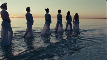 Movie still from “Lemonade” (2016), directed by Mark Romanek – A group of women walking through the water at the beach; Wide shot, Low angle