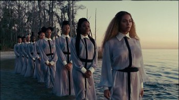 Movie still from “Lemonade” (2016), directed by Mark Romanek – A group of women standing next to each other in front of a body of water; Extreme Wide shot, Over the shoulder angle