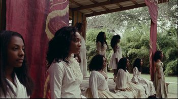 Movie still from “Lemonade” (2016), directed by Mark Romanek – A group of women in white dresses sitting on a bench; Wide shot, Over the shoulder angle