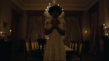 Movie still from “Lemonade” (2016), directed by Mark Romanek – A woman in a white dress standing in front of a chandelier; Medium shot, Low angle