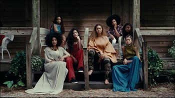 Movie still from “Lemonade” (2016), directed by Mark Romanek – A group of women sitting on a wooden porch; Wide shot, Low angle