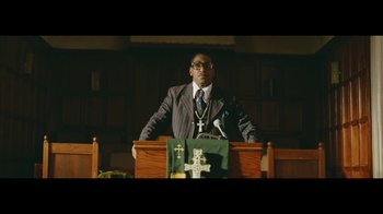 Movie still from “Lemonade” (2016), directed by Mark Romanek – A man standing at the top of a podium in front of a microphone; Medium shot, Low angle