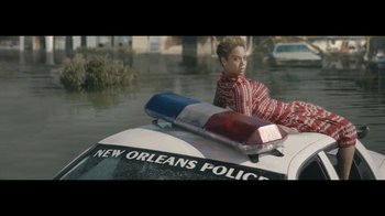 Movie still from “Lemonade” (2016), directed by Mark Romanek – A woman sitting on top of a police car in a flooded area; Extreme Wide shot, High angle