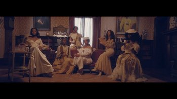 Movie still from “Lemonade” (2016), directed by Mark Romanek – A group of people sitting on top of a red couch; Wide shot, High angle