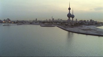 Movie still from “Lessons of Darkness” (1992), directed by Werner Herzog – A body of water near a city at dusk; Extreme Wide shot, High angle
