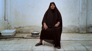 Movie still from “Lessons of Darkness” (1992), directed by Werner Herzog – A woman sitting on the ground wearing a black veil; Wide shot, Low angle