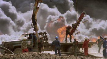 Movie still from “Lessons of Darkness” (1992), directed by Werner Herzog – A group of people standing on top of a pile of dirt; Extreme Wide shot, High angle