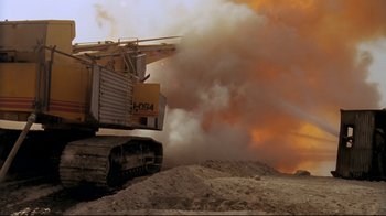Movie still from “Lessons of Darkness” (1992), directed by Werner Herzog – A large construction vehicle is in the dirt; Extreme Wide shot, Low angle