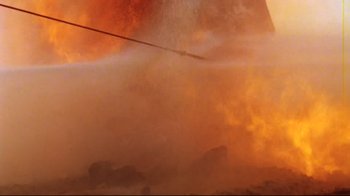 Movie still from “Lessons of Darkness” (1992), directed by Werner Herzog – A large amount of smoke coming out of a building; Wide shot, Low angle