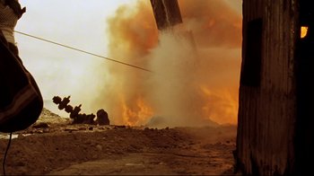 Movie still from “Lessons of Darkness” (1992), directed by Werner Herzog – Smoke billows out of a power line as a fire rages; Extreme Wide shot, Low angle