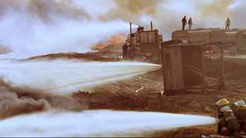 Movie still from “Lessons of Darkness” (1992), directed by Werner Herzog – Some people are standing on the side of the road; Extreme Wide shot, Low angle