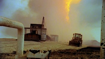 Movie still from “Lessons of Darkness” (1992), directed by Werner Herzog – An image of an industrial area with a lot of smoke coming out of the sky; Extreme Wide shot, Low angle